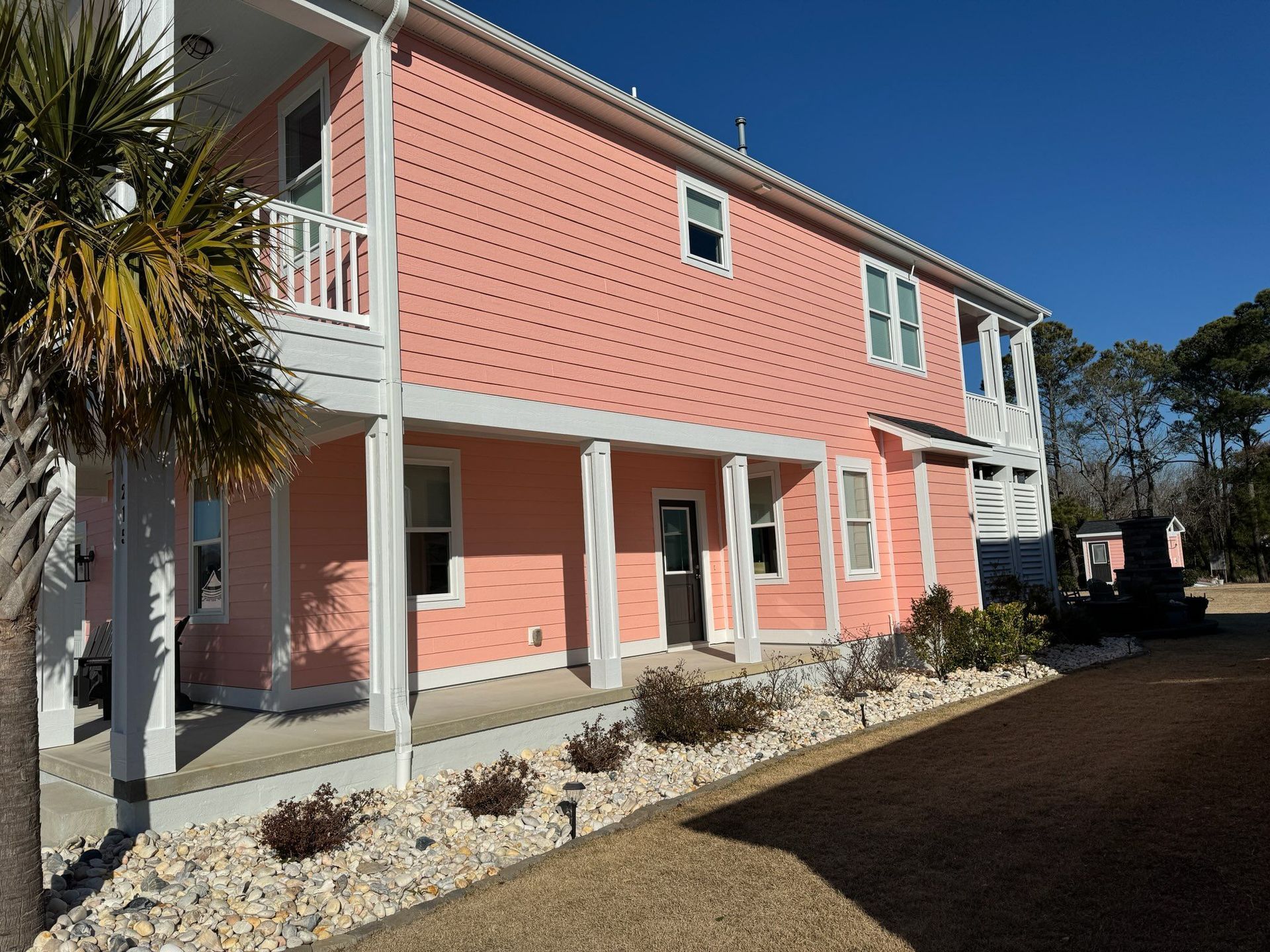 A pink and white house with a palm tree in front of it