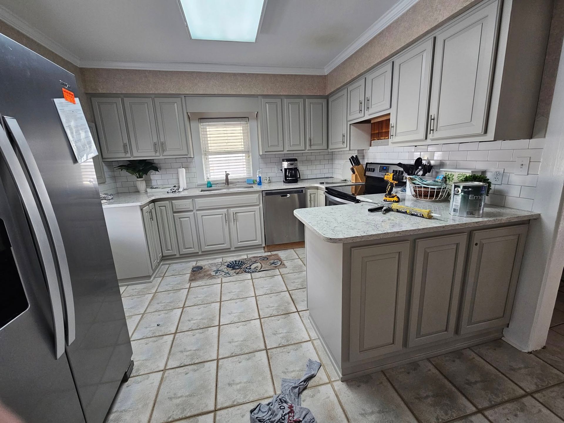 A kitchen with white cabinets and a stainless steel refrigerator.