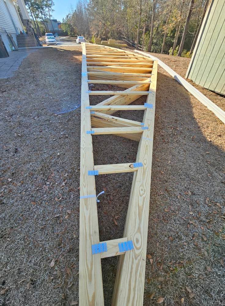 A wooden ladder is sitting on top of a gravel road.