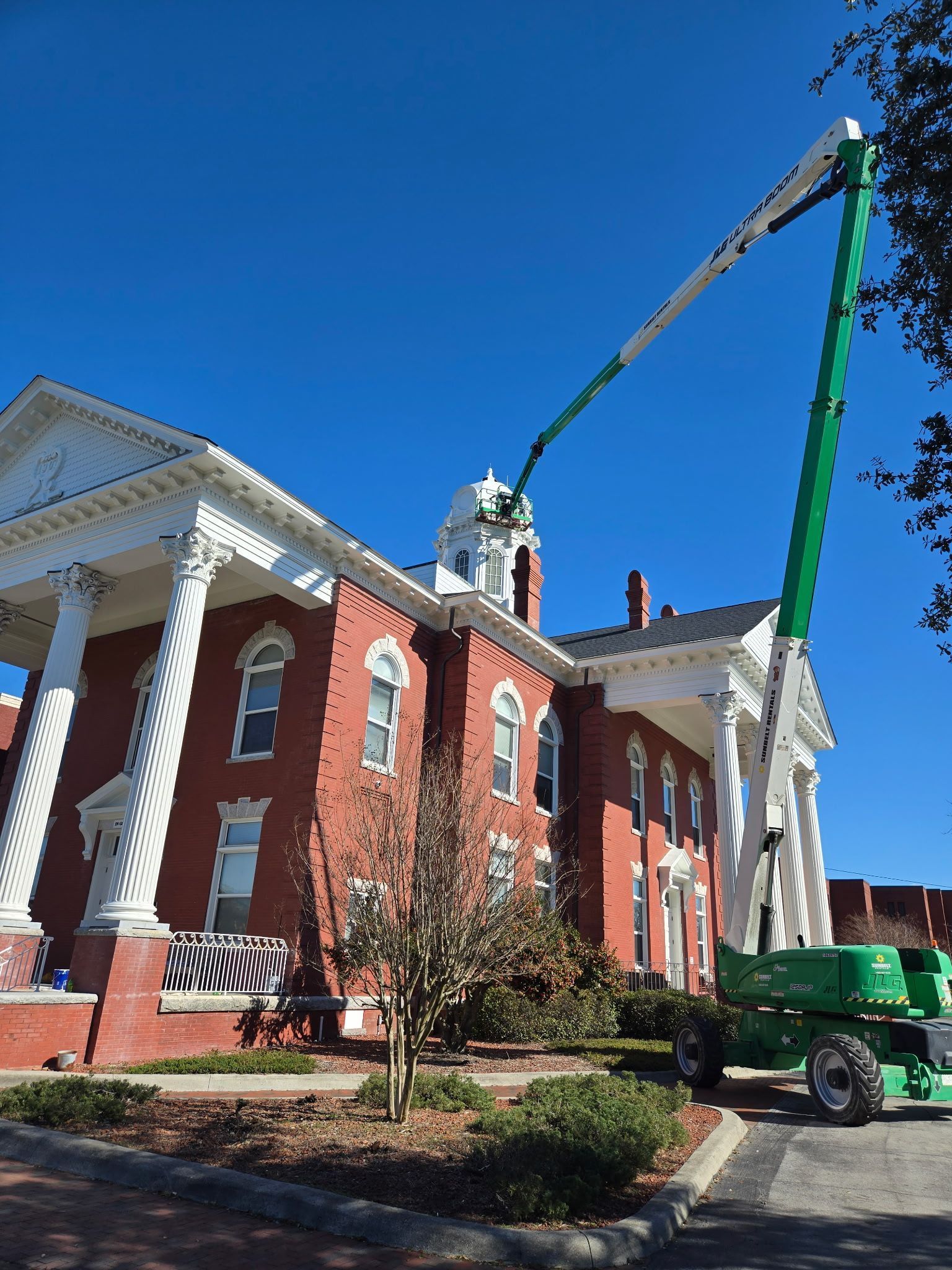 A large brick building with a green crane in front of it
