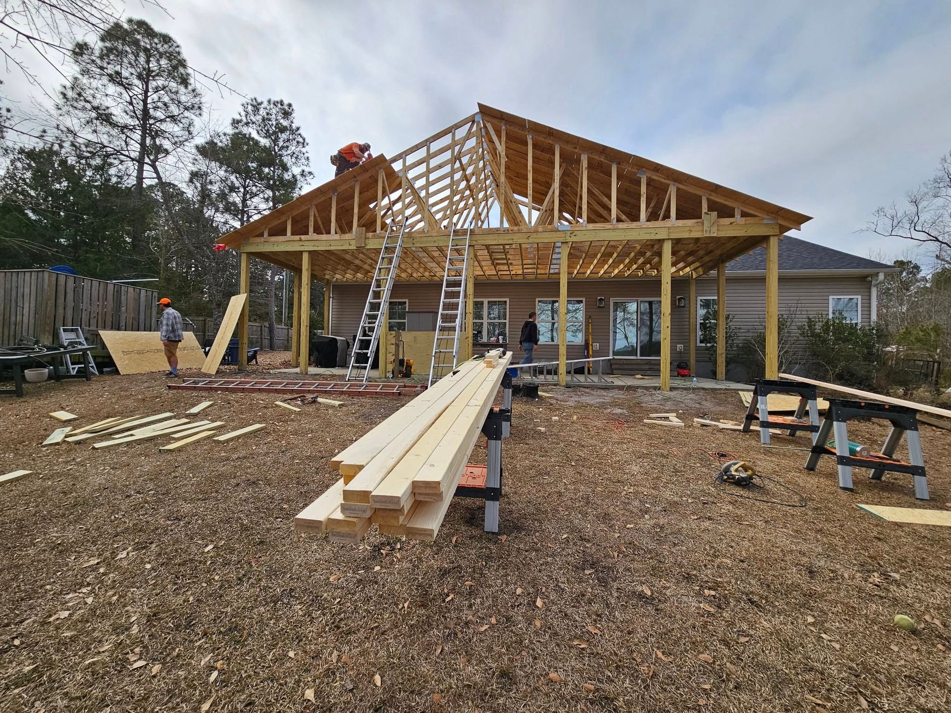 A large wooden structure is being built in a backyard.
