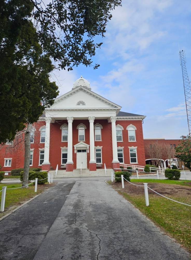 A large red brick building with columns and a driveway leading to it