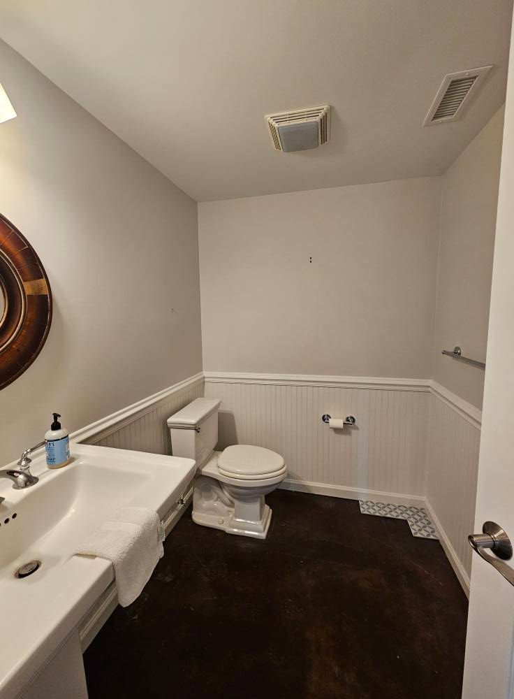 A bathroom with a toilet , sink and mirror.
