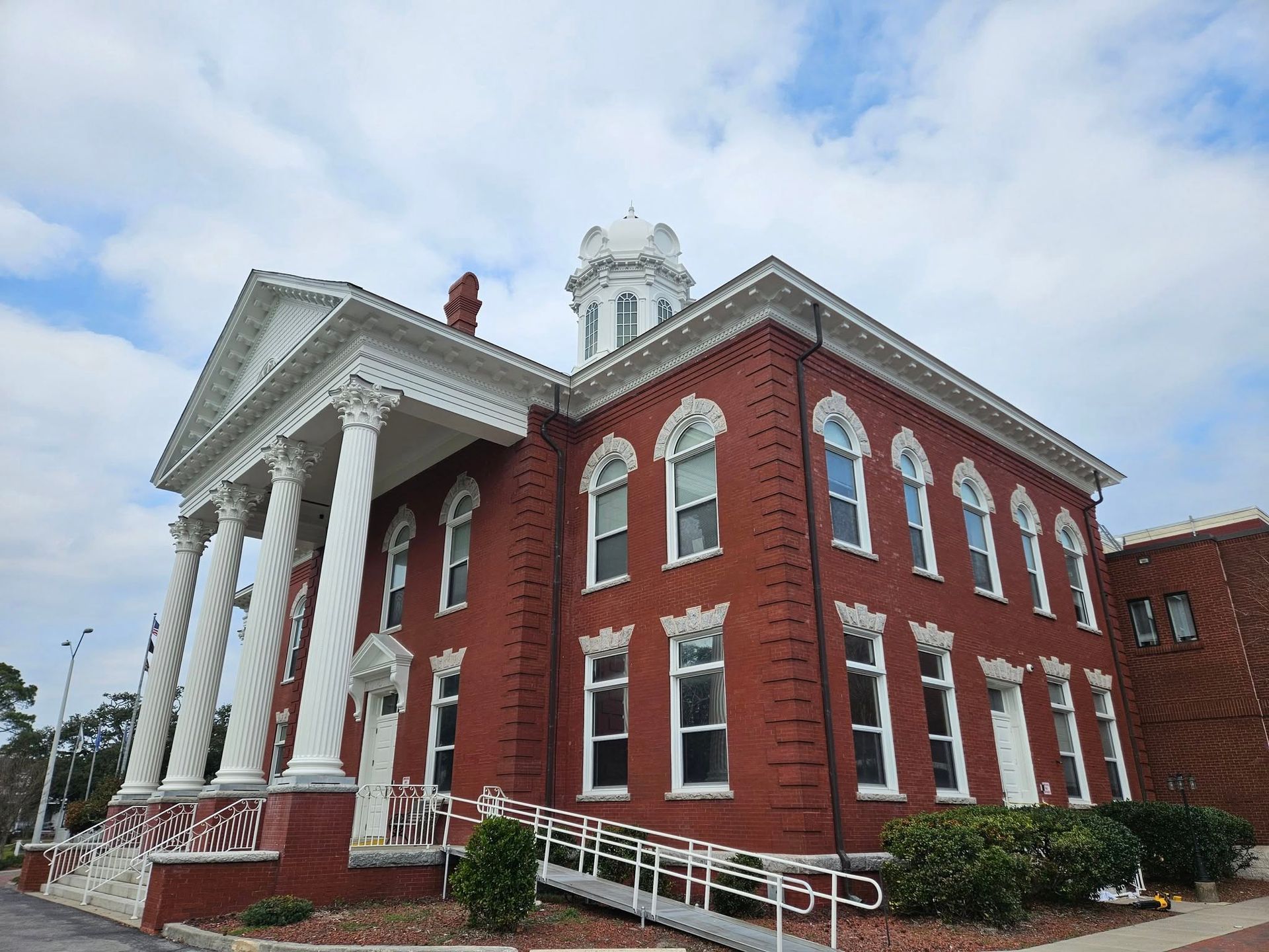 A large red brick building with white columns and a clock tower.