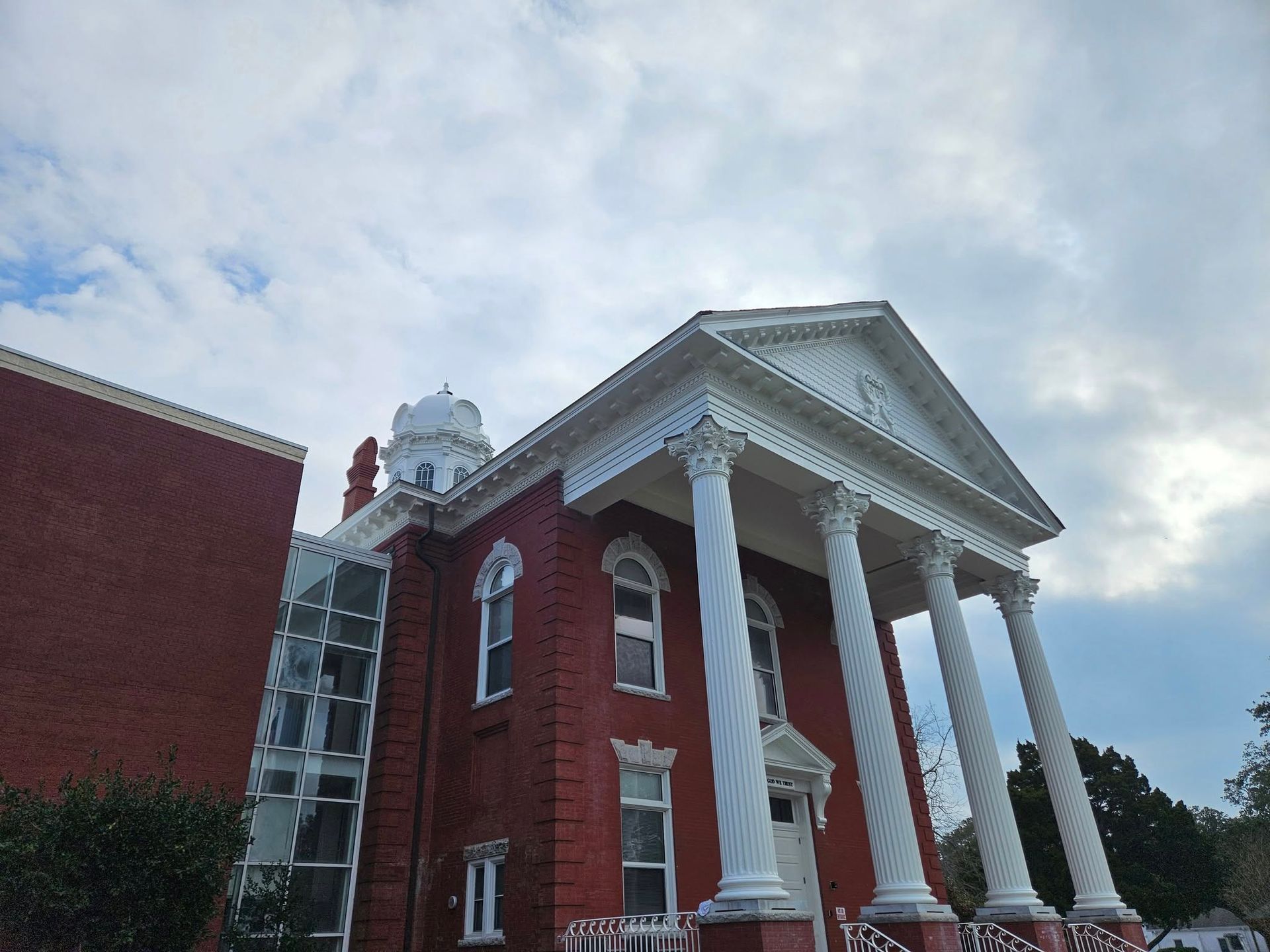A large red brick building with white columns and a clock tower