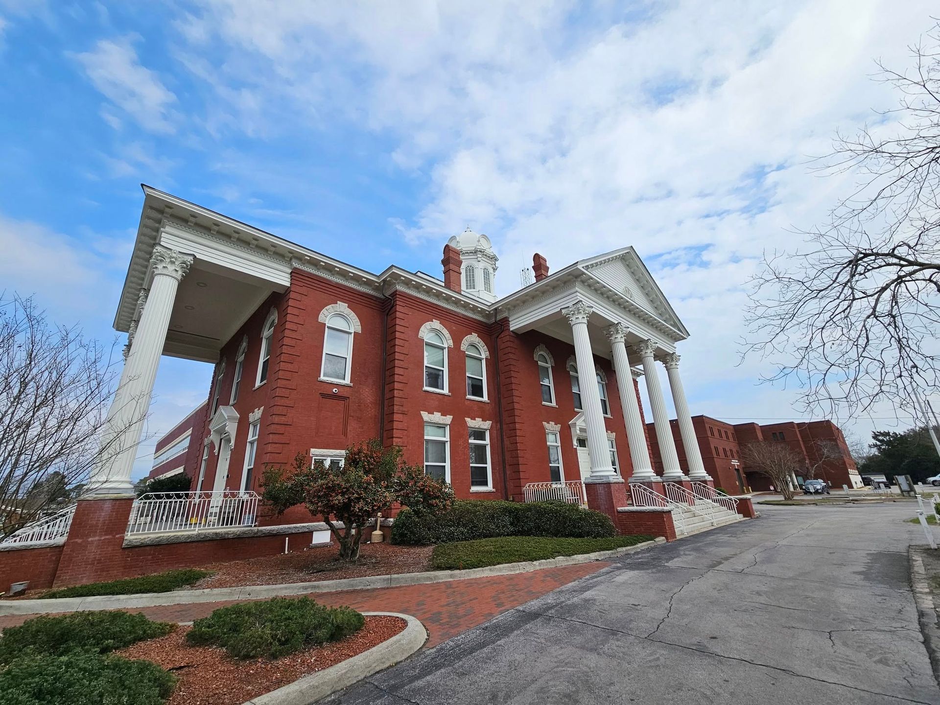 A large red brick building with white columns and a clock on top of it.