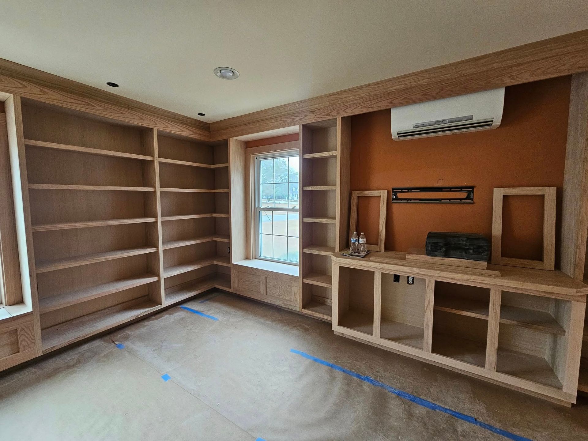 A room with a lot of shelves and a window.
