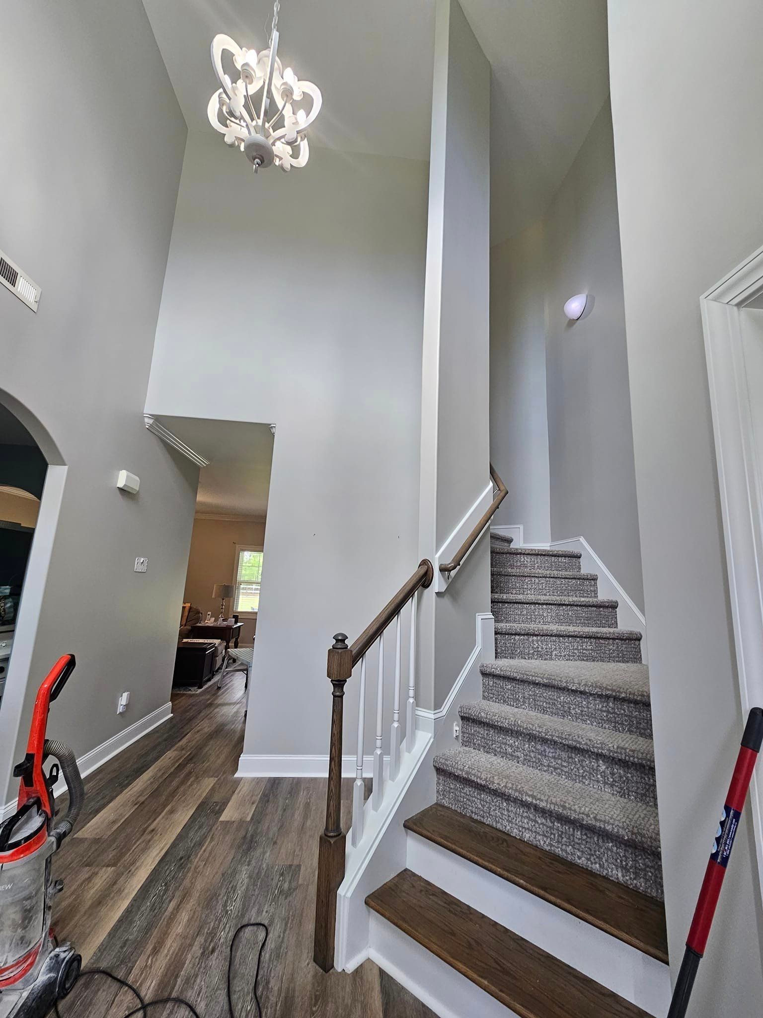 A vacuum cleaner is sitting in a hallway next to a set of stairs.