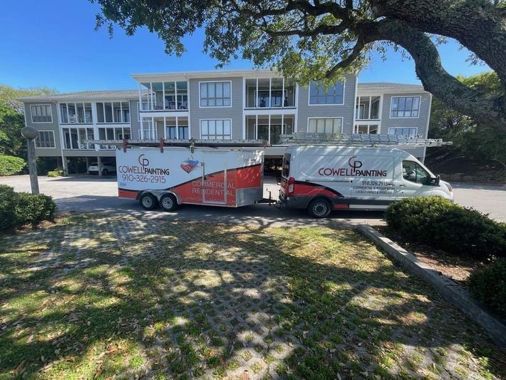 Two vans are parked in front of a large building.