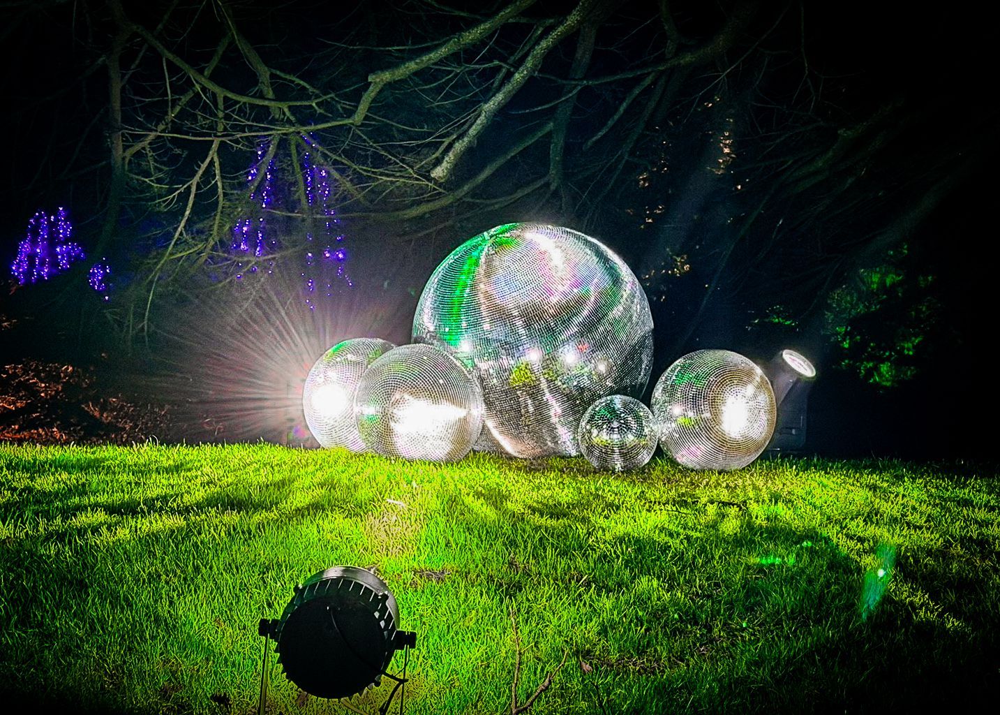 Mirror ball centerpiece illuminated by spotlights creating sparkling walk-through display.