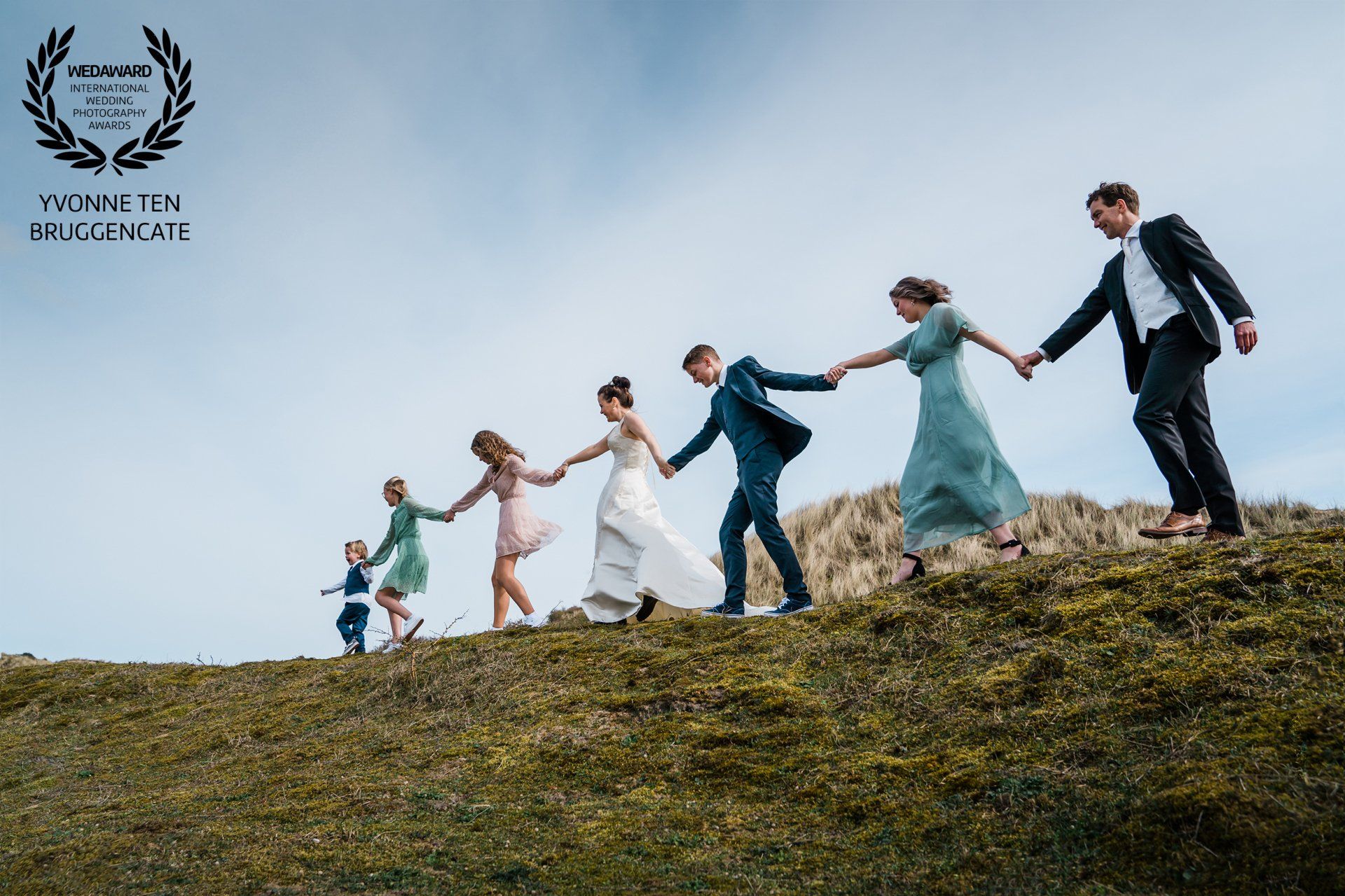 Een groep mensen die hand in hand een heuvel oplopen.