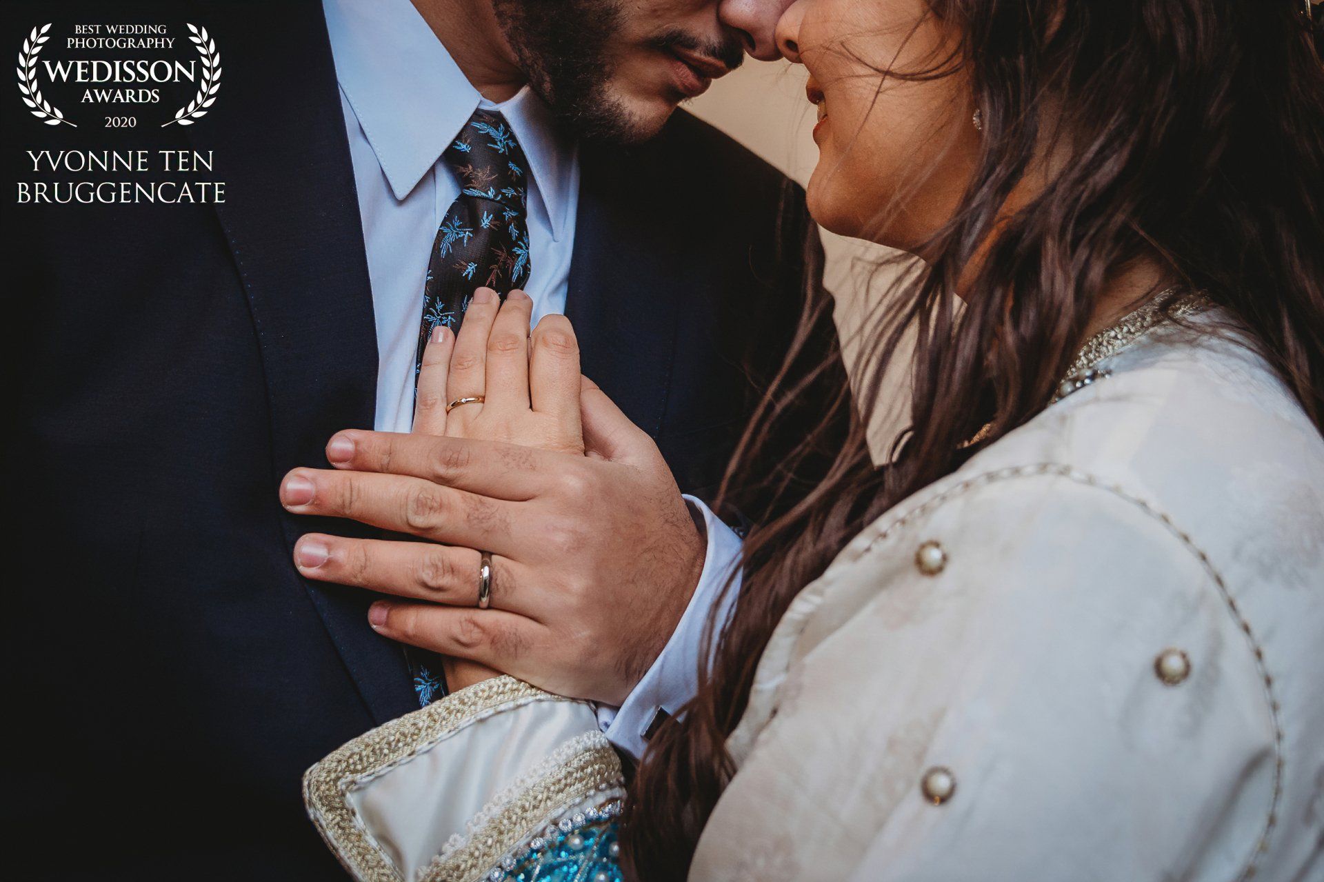 Een man in pak en stropdas kust een vrouw op het voorhoofd.