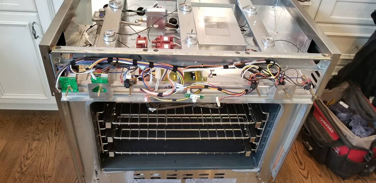 A stove with the door open and a bunch of wires coming out of it.