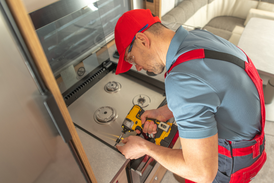 A man is working on a stove in a kitchen.