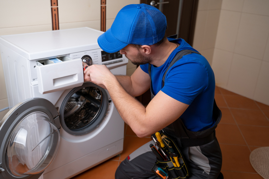 A man is fixing a washing machine in a bathroom.