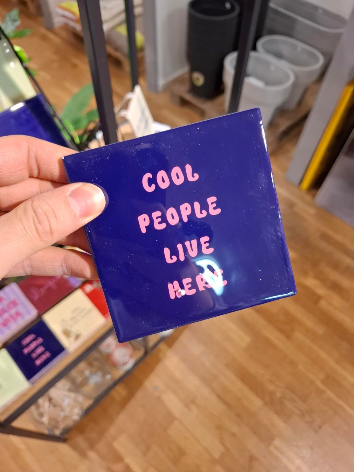 Een hand houdt een donkerblauw vierkant bord vast met de tekst