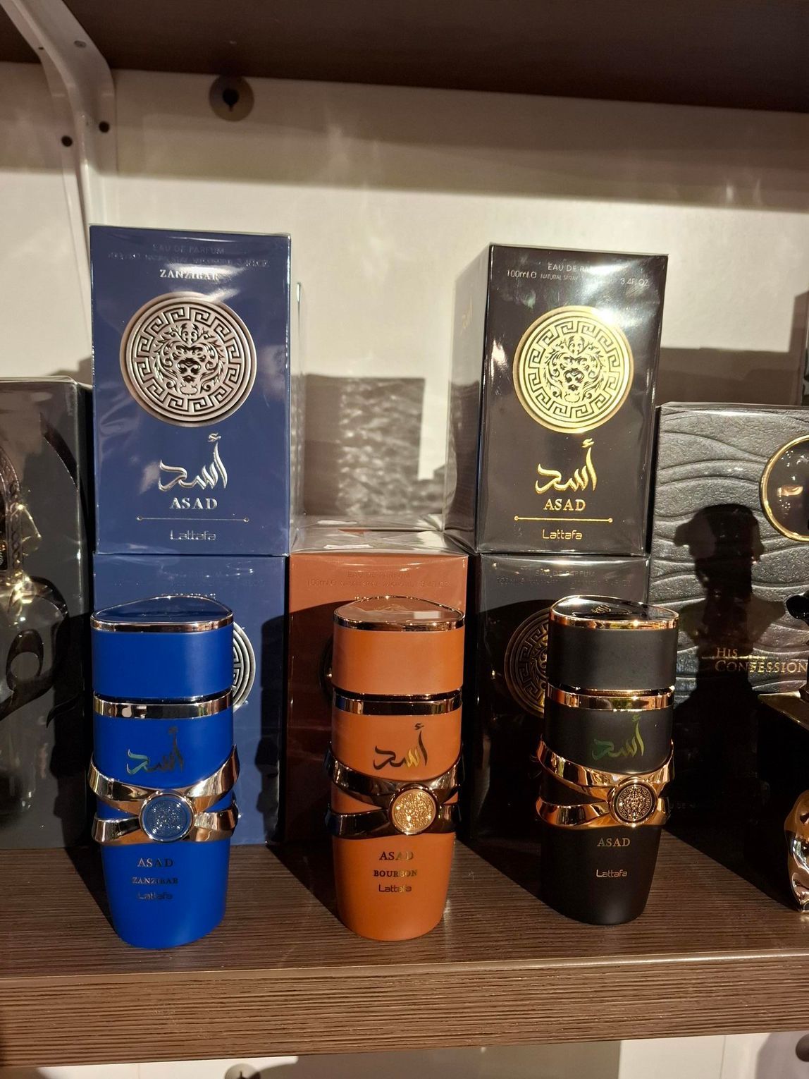 Parfumflesjes in roze, rood, wit en geel staan uitgestald op een houten plank in een winkel.
