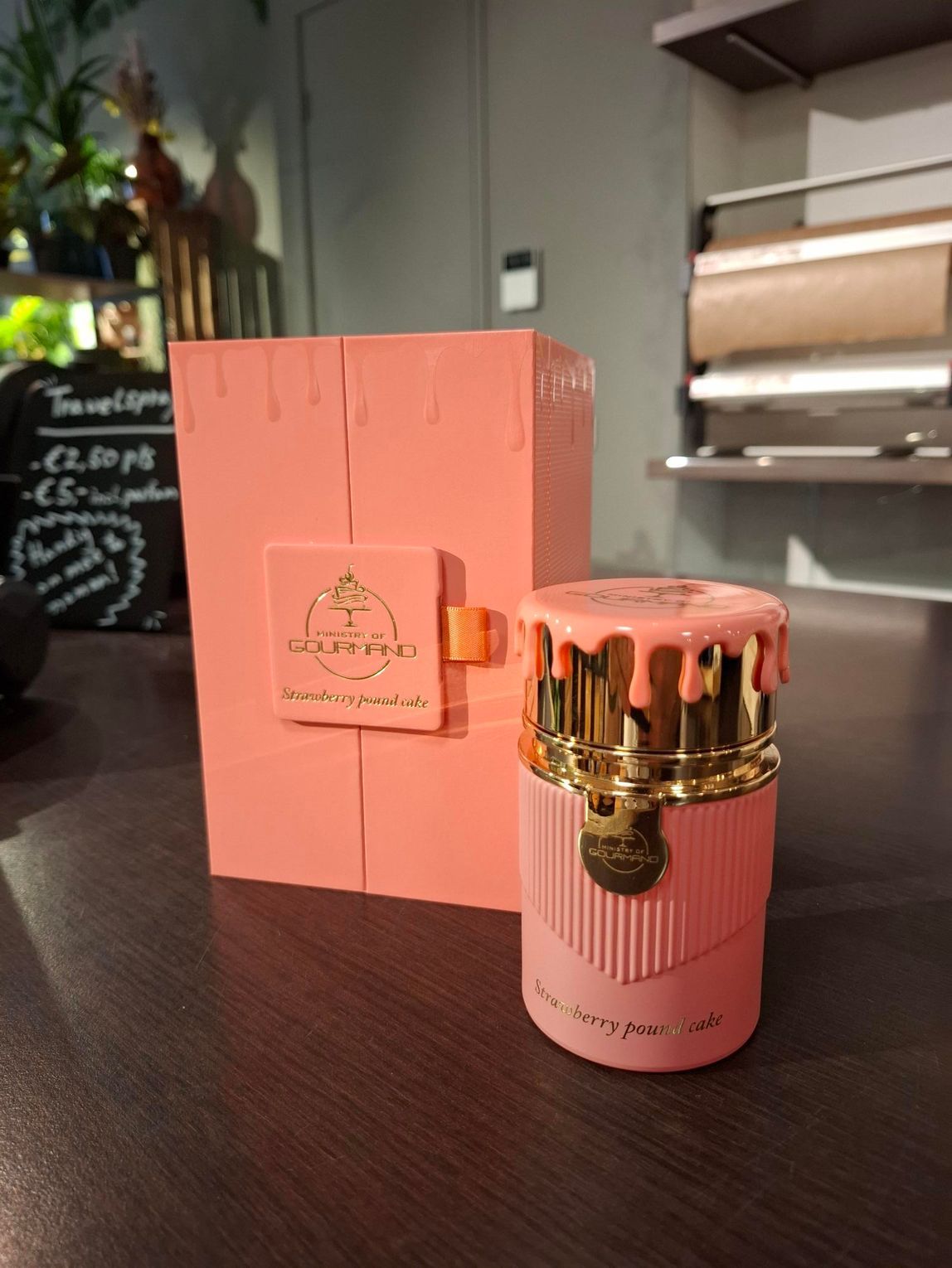Een koraalkleurig parfumflesje met een dop in de vorm van smeltwas staat naast de bijpassende, hoge rechthoekige doos.