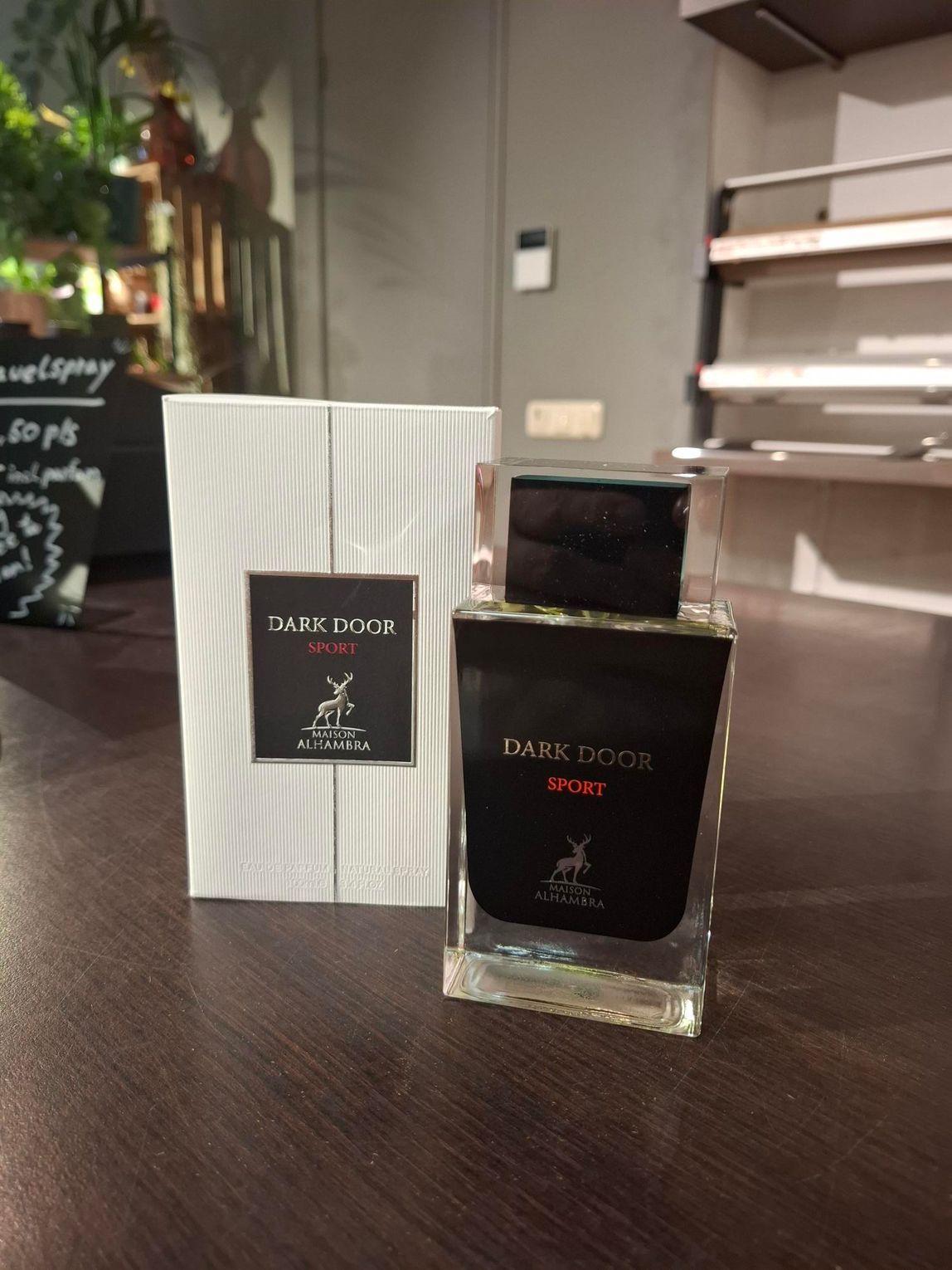 Een fles Dark Doge-parfum en de bijbehorende witgestreepte doos staan op een donkerhouten oppervlak in een winkelomgeving.
