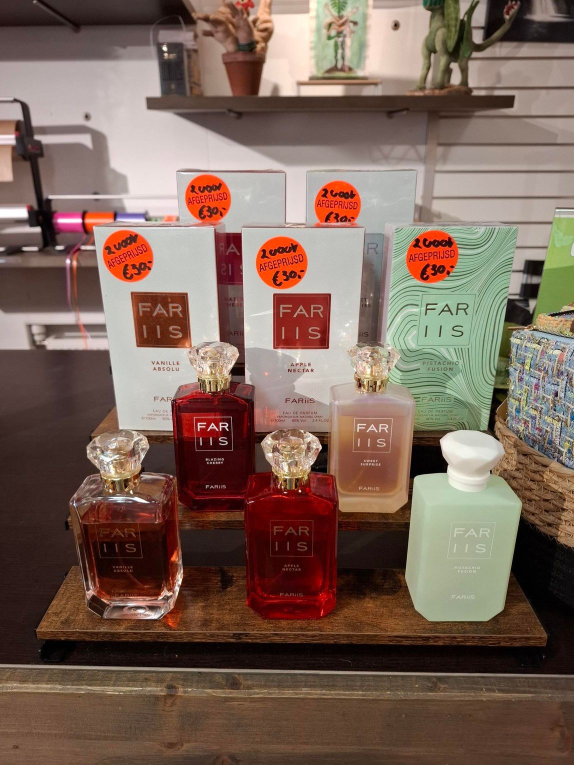 Vier flesjes Kayali-parfum in verschillende kleuren staan uitgestald op een rond, grijs kleed van imitatiebont.