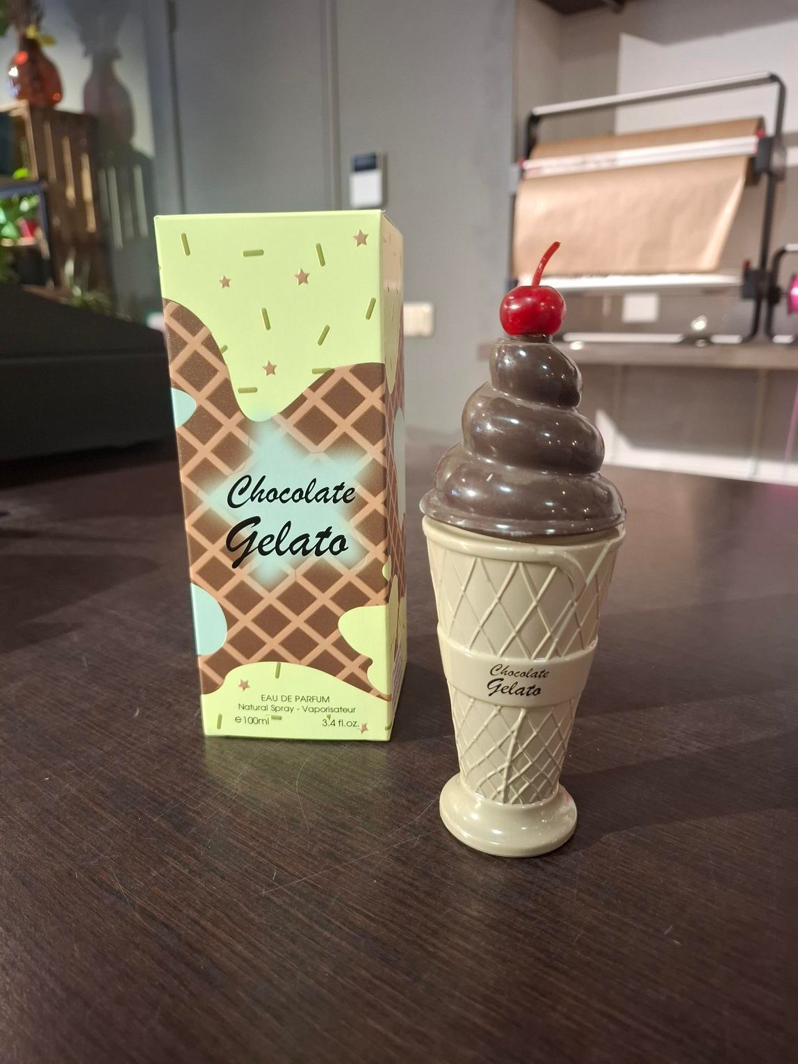 Een bakje chocolade-ijs naast een softijshoorntje met chocolade en een kers erop.