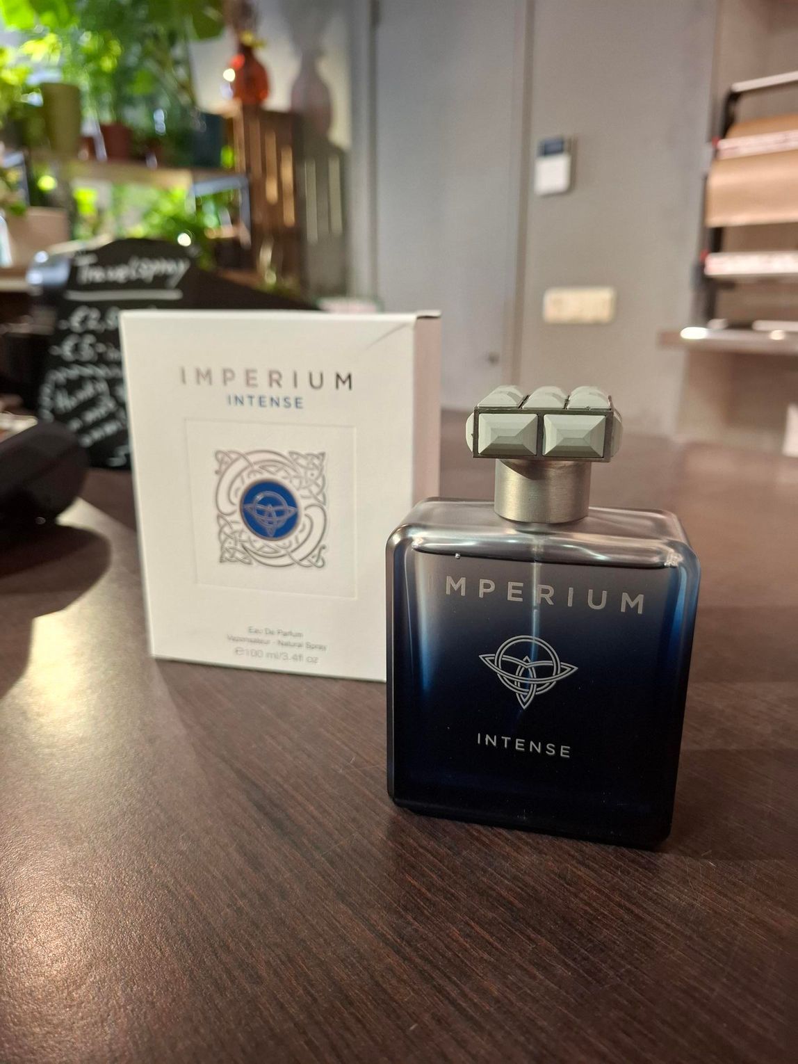 Het parfumflesje Imperium van Atkinsons staat naast de doos op een houten tafel.