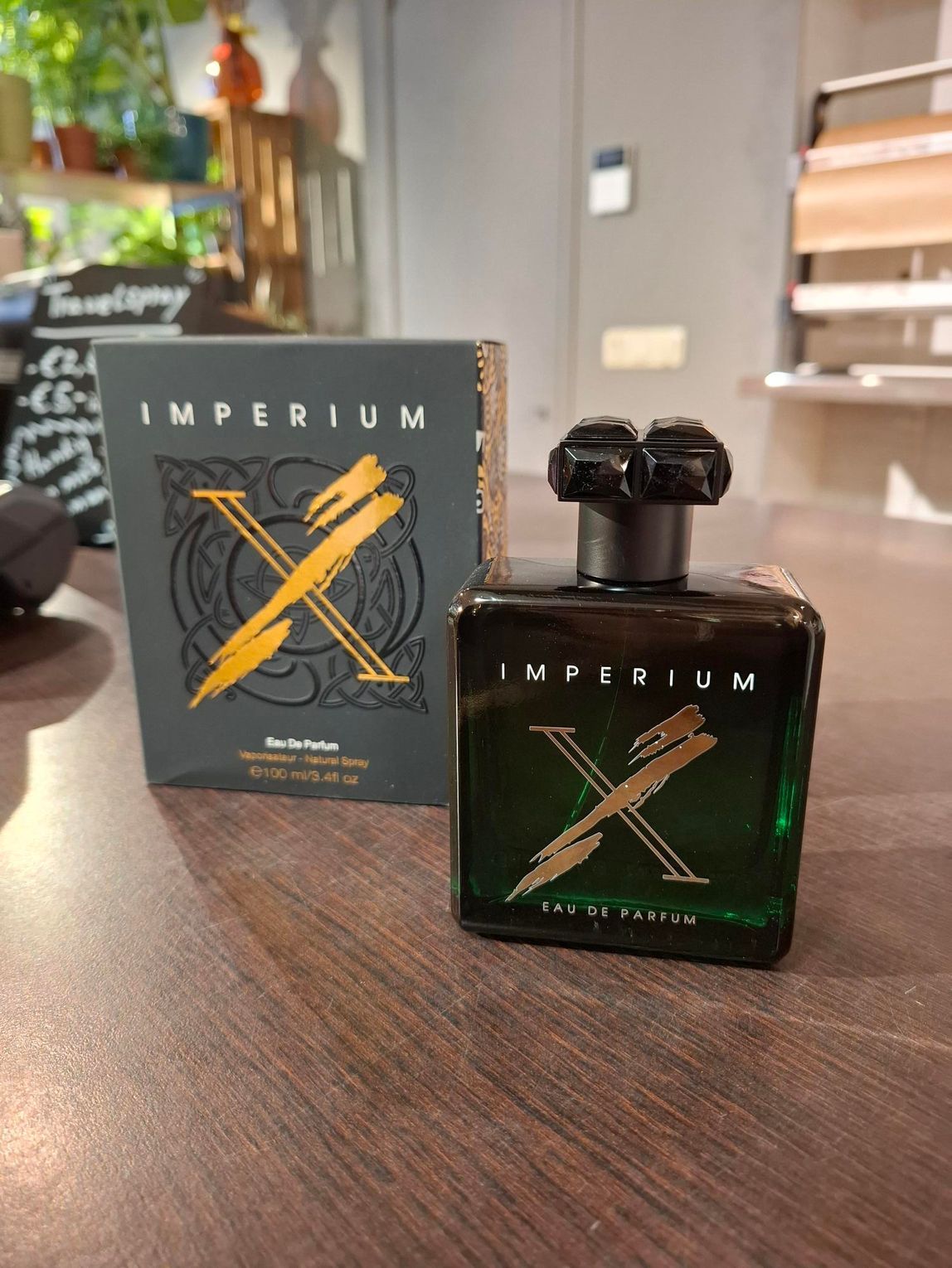 Een flesje Black Imperium parfum met gouden versiering staat naast de doos op een tafel in een winkel.