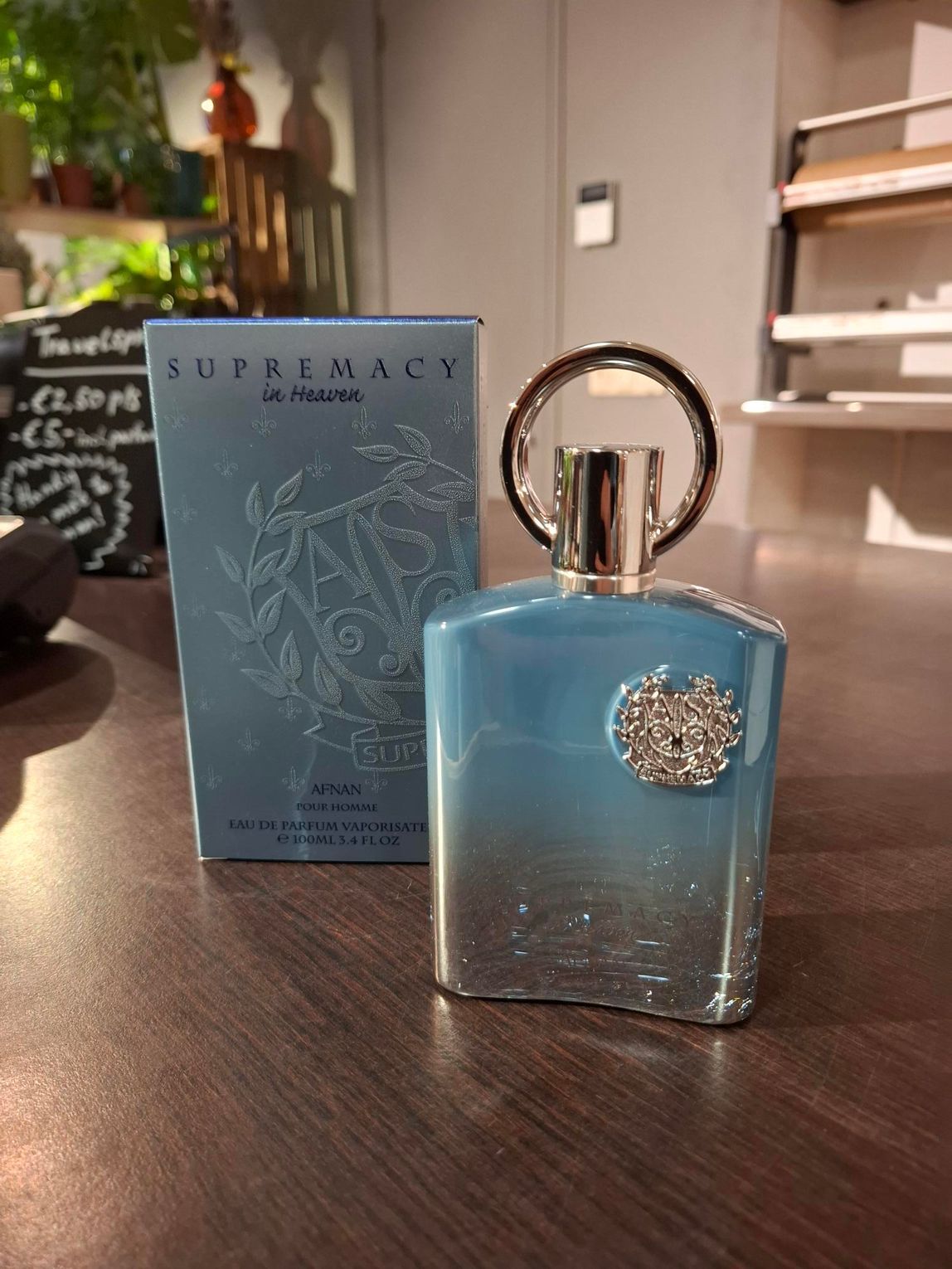 Blauwe parfumfles met sierlijke zilveren dop naast een bijpassende doos op een houten tafel.
