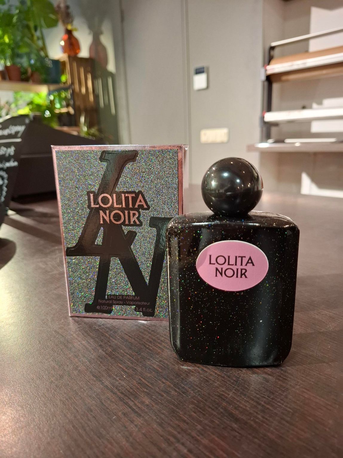 Parfumflesje en doosje van Lolita Noir op een tafel, zwart flesje met roze etiket.