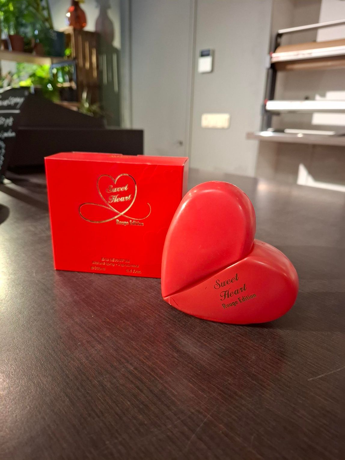 Twee rode, hartvormige doosjes op een tafel, een open en een gesloten, met daarachter een bijpassende rode geschenkdoos.