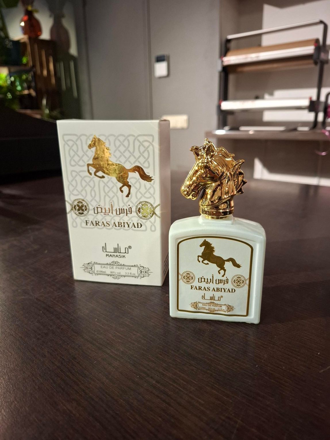 Parfumflesje en bijpassend doosje op een donkere tafel in een zacht verlichte kamer.
