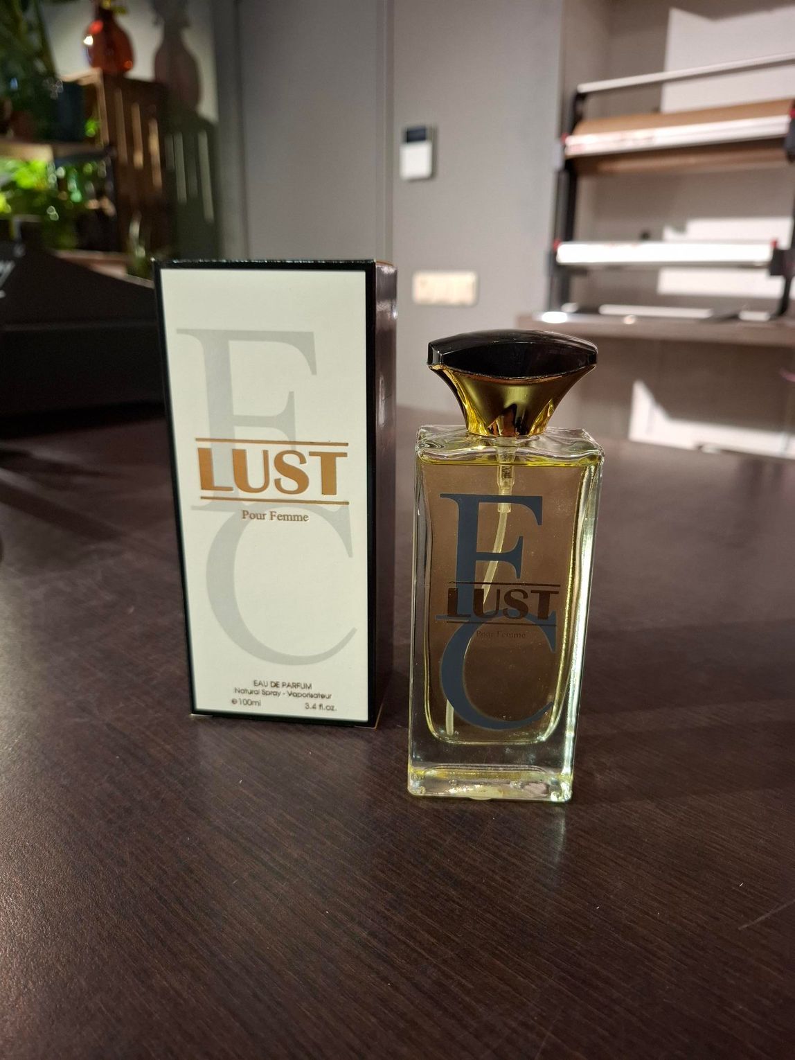 Parfumflesje en -doosje op een donkere tafel in een moderne kamer.