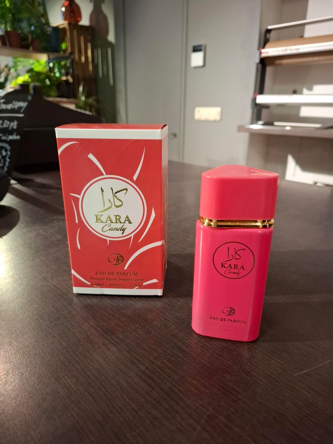 Een roze parfumflesje naast een bijpassende rood-witte doos op een aanrecht binnenshuis.