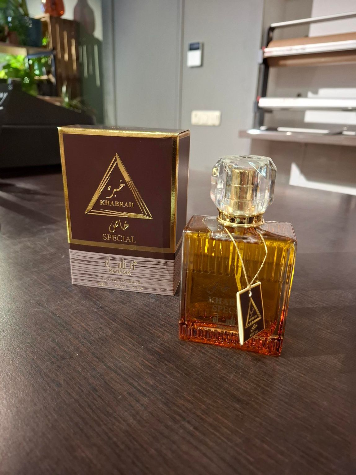Een amberkleurige parfumfles met een bijpassend doosje op een donkere tafel in een kamer.