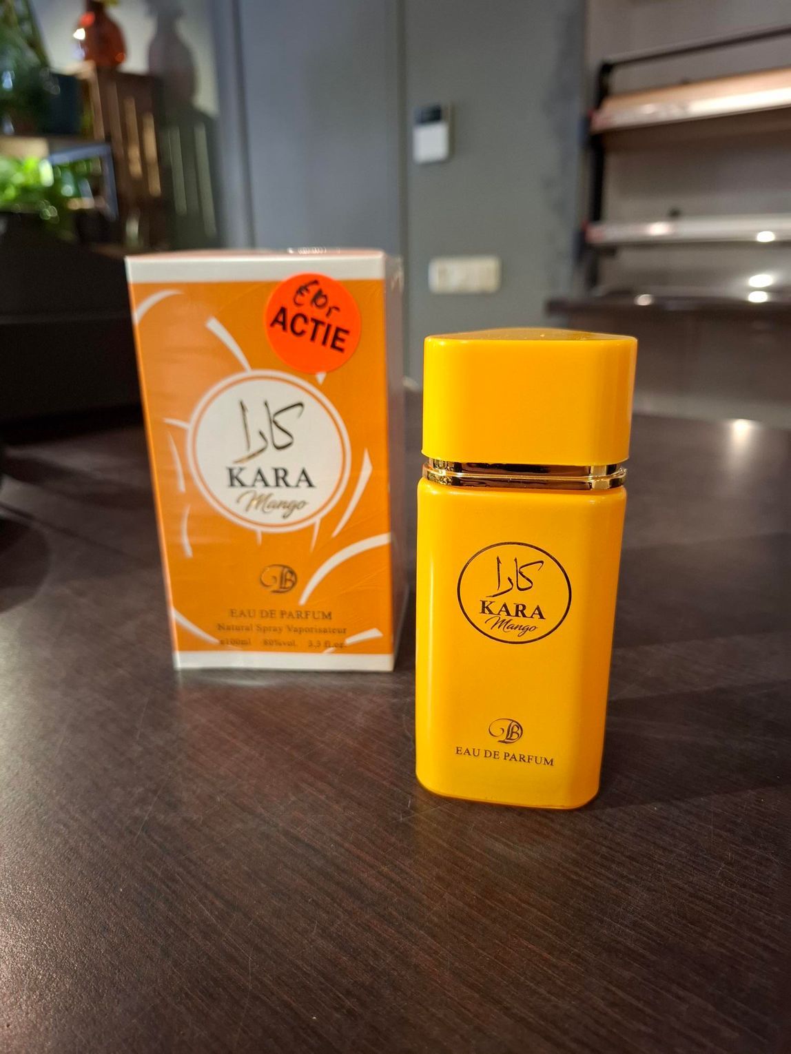 Oranje KARA parfumflesje en bijpassend doosje op een tafel binnen.