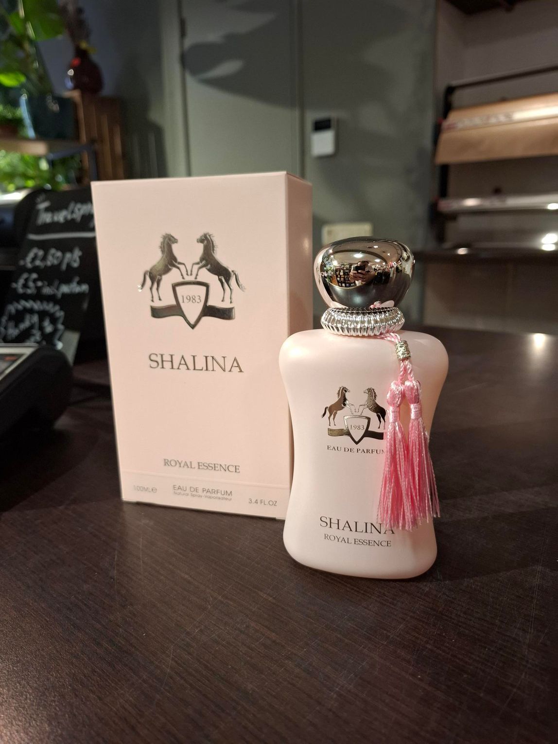 Roze Shalina parfumflesje met doos op een donkere tafel binnen.