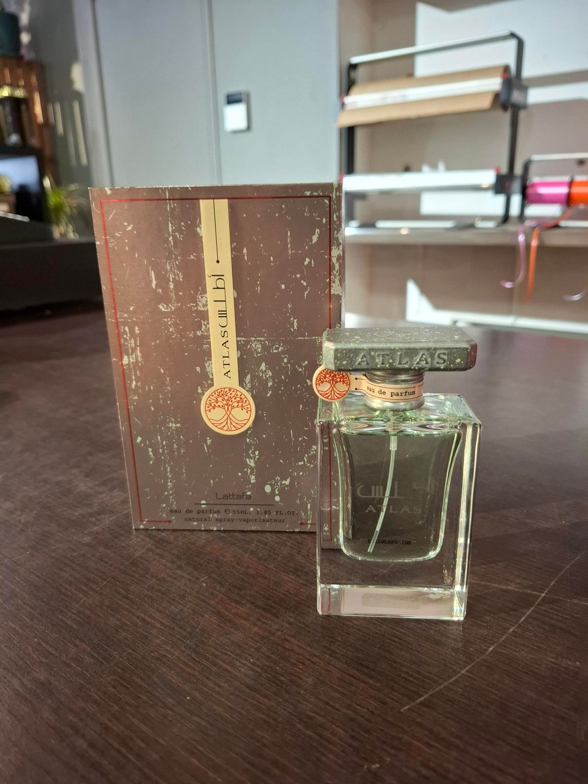 Parfumflesje en -doos op een tafel in een kamer met planken op de achtergrond.