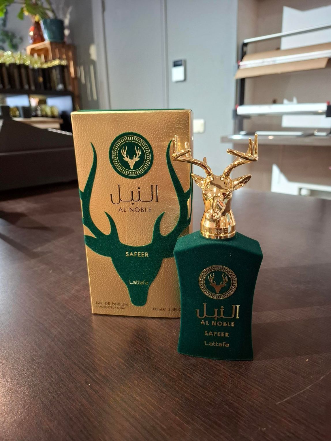 Groene en gouden parfumfles naast een bijpassende gouden doos op een tafel binnen.