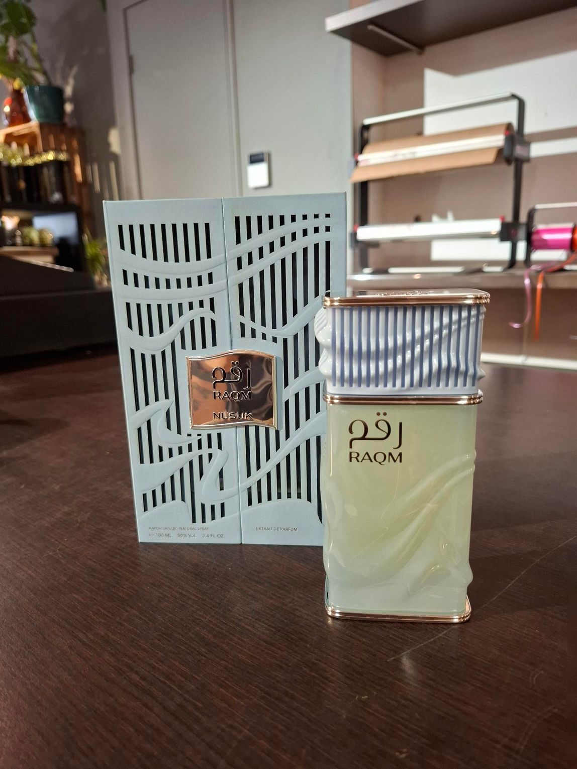 Parfumflesje met zilveren dop naast de doos met patroon op een houten tafel binnen.