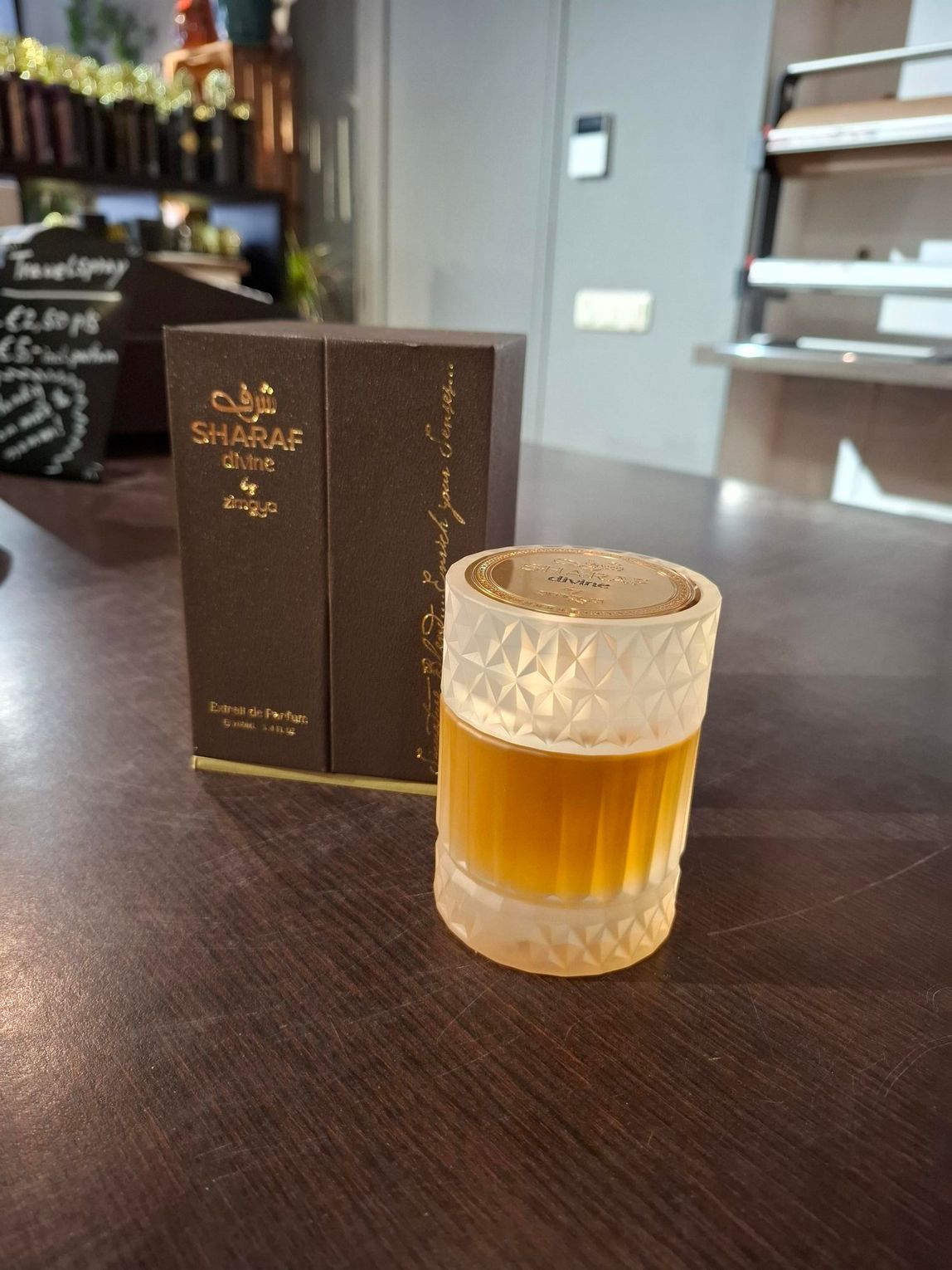 Een klein whiskyglas met een amberkleurige drank ernaast, naast een bruine doos op een tafel in een bar.