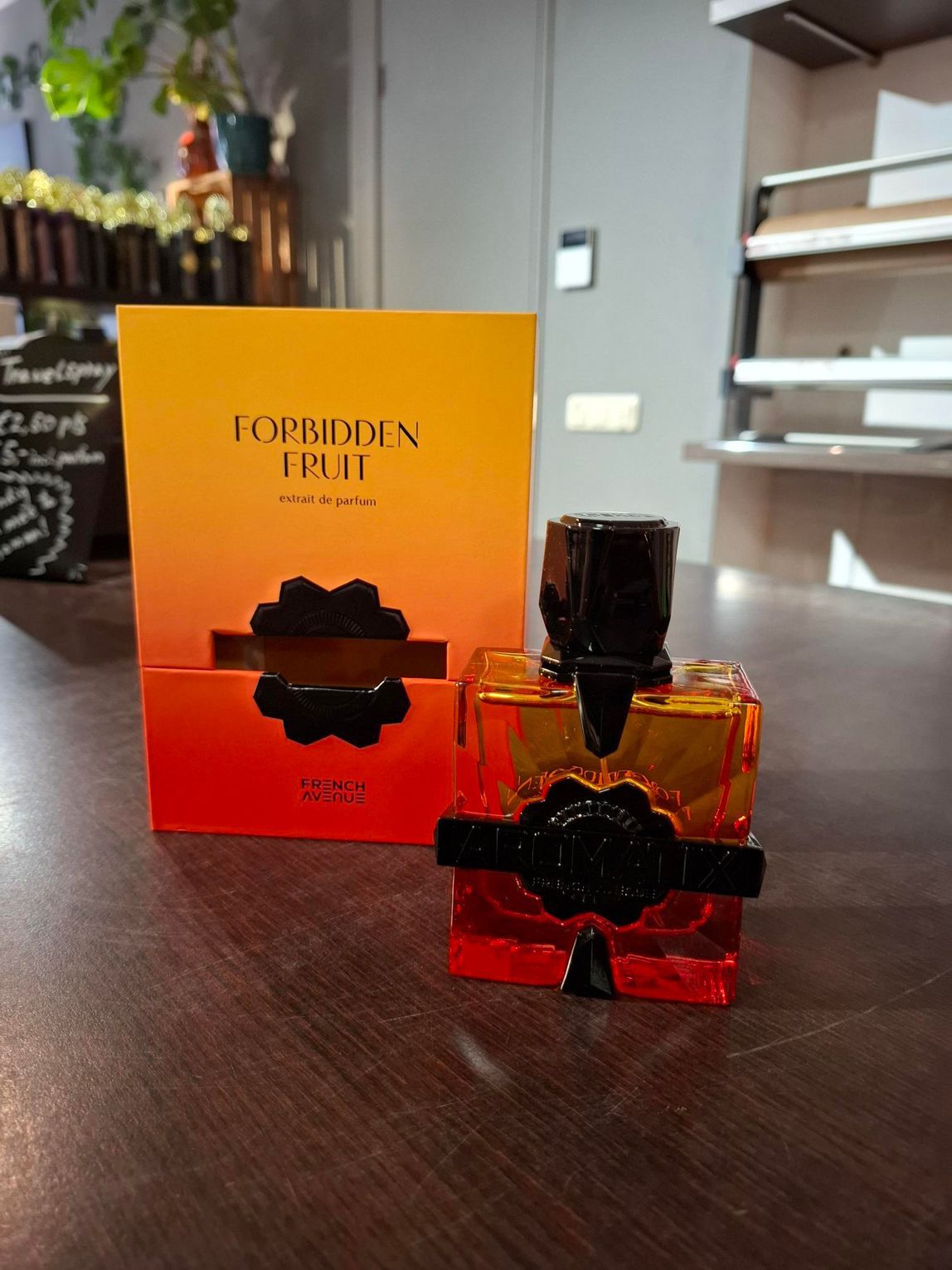 Parfumdoos en -flesje Perfumed Fruit op een tafel, met oranje-rode verpakking en donkere dop.