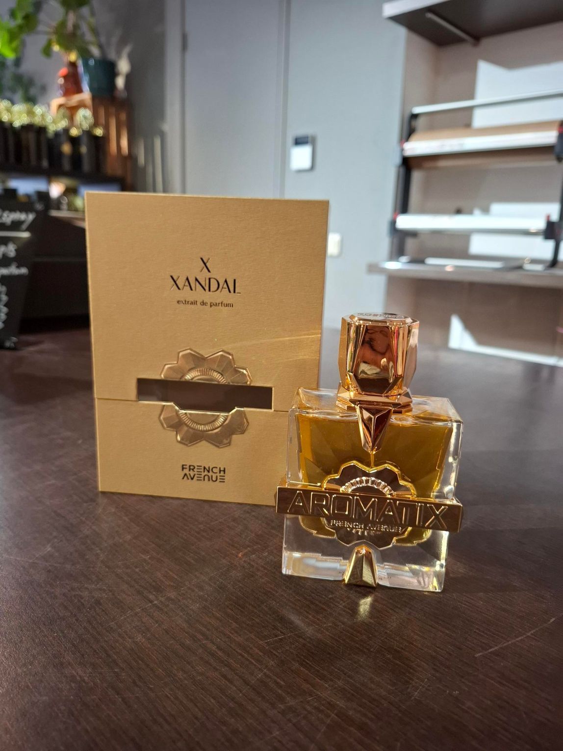 Een amberkleurig parfumflesje naast een bijpassende gouden doos op een donkere houten tafel.