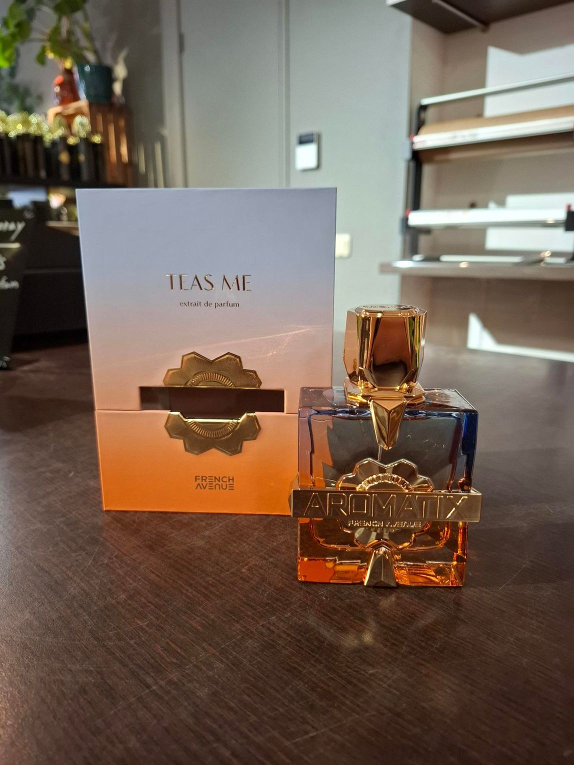Parfumflesje en -doosje op een houten tafel in een zacht verlichte kamer.