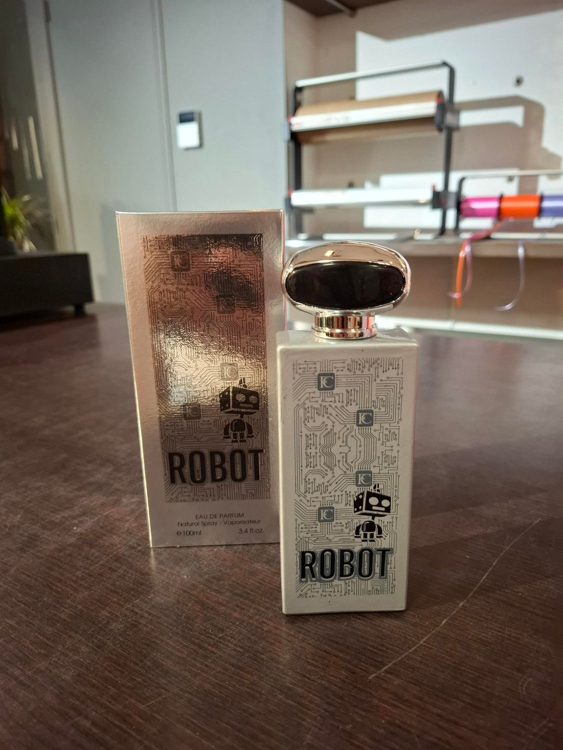 Twee ROBOT-parfumflesjes op een tafel, met een zilveren doos en wazige planken op de achtergrond.