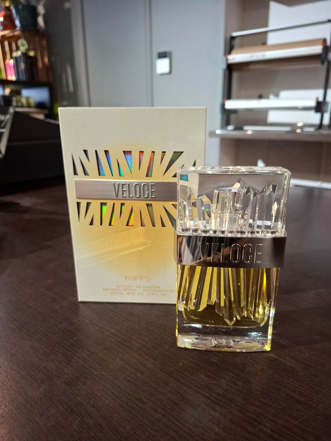 Parfumflesje naast bijpassend doosje op een donkere tafel in een kamer.