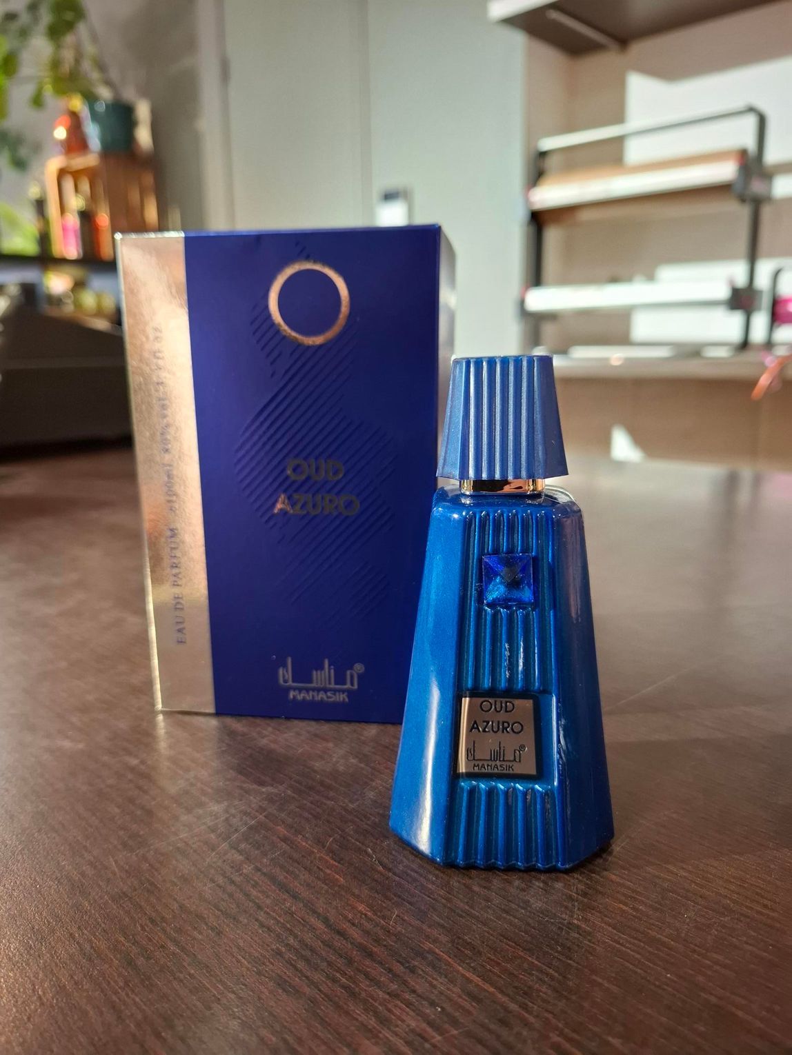 Een blauw parfumflesje naast een bijpassende blauwe doos op een houten tafel binnenshuis.