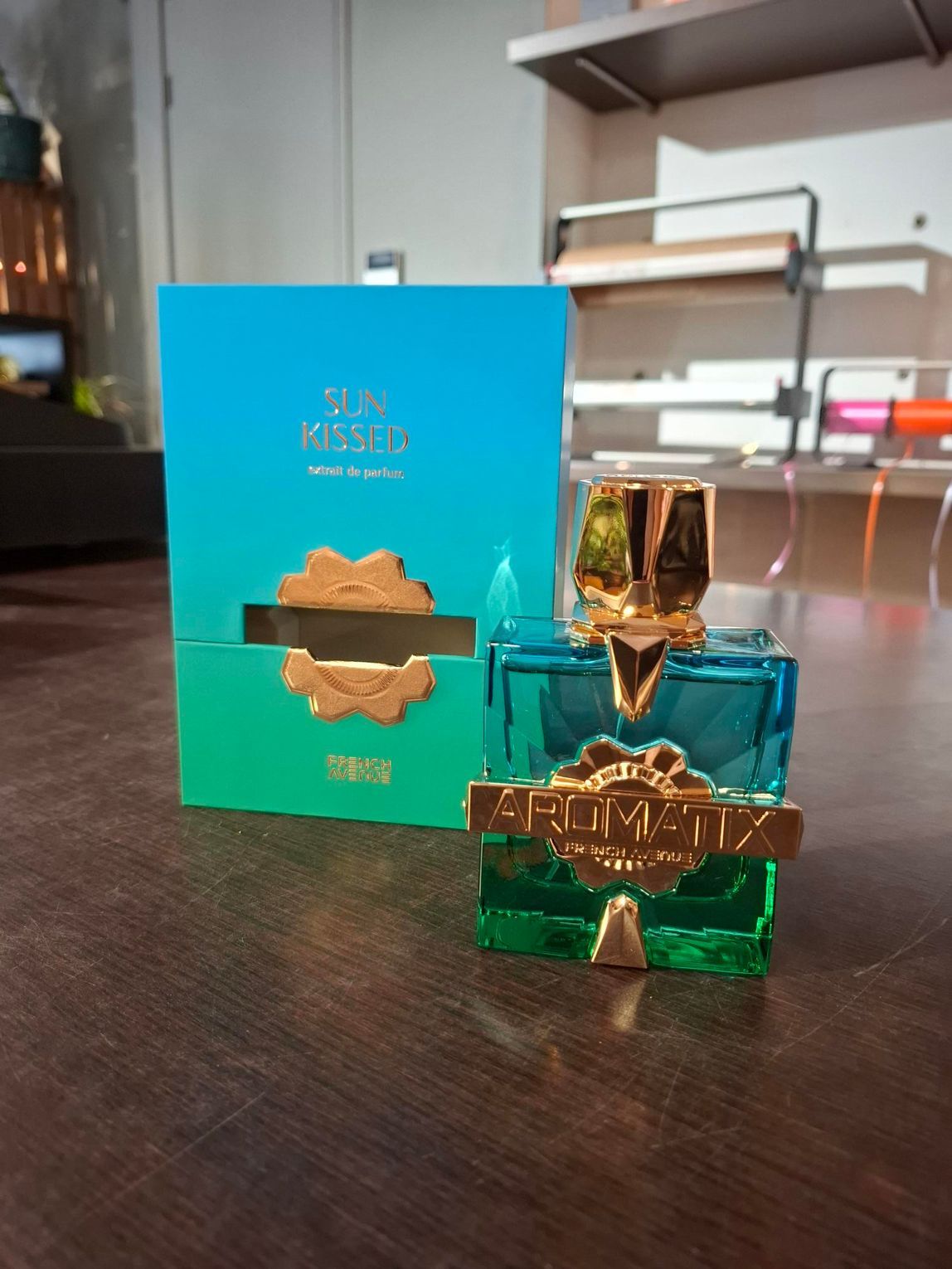 Twee turquoise parfumflesjes met gouden dopjes op een donkere tafel, met daarachter een bijpassende turquoise doos.