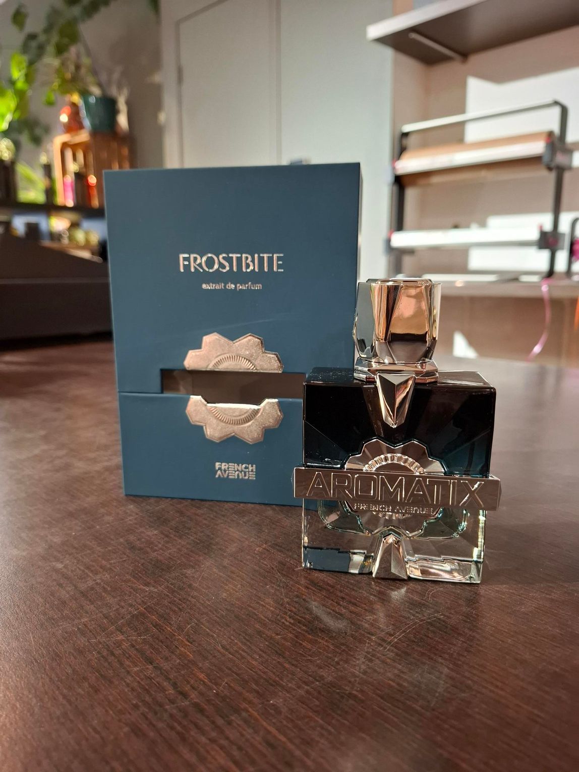 Een flesje en doosje Frostbite-parfum op een houten tafel in een zacht verlichte kamer.