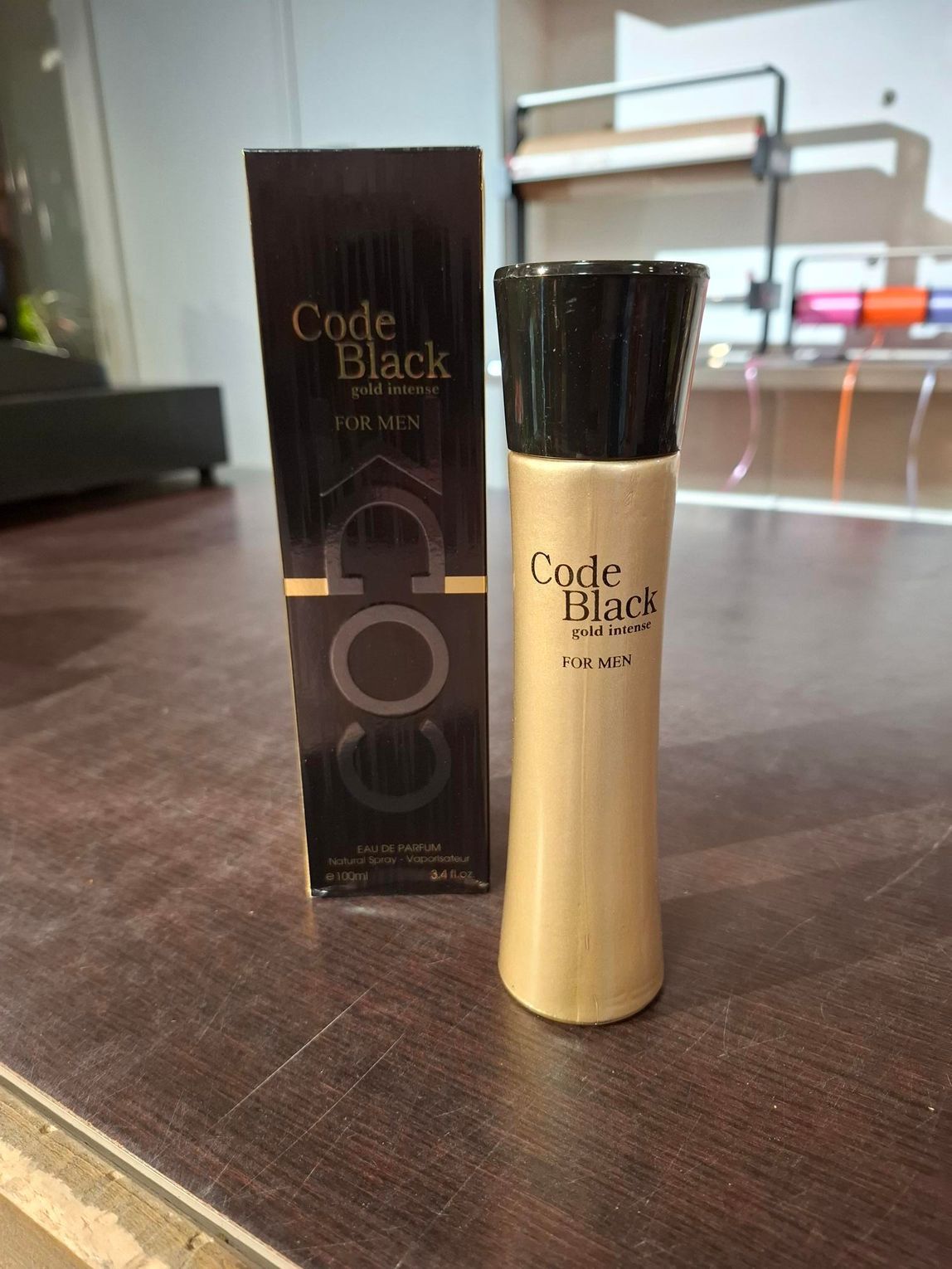 Het parfumflesje Coco Mademoiselle staat naast de zwarte doos op een houten tafel.