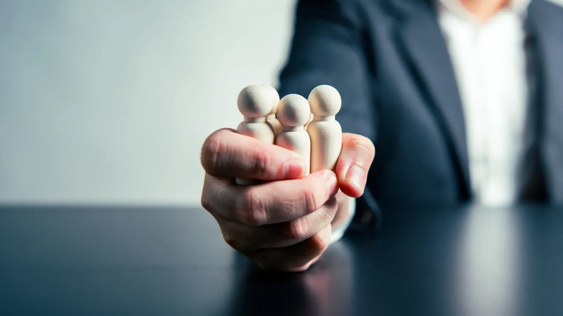 Image of hand grasping wooden shapes of people